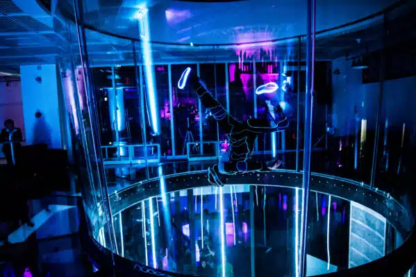 Person flying in dark with neon lights at Fly Station indoor skydiving